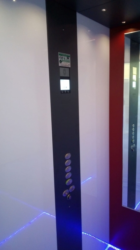 interno della cabina con specchio, parete di fondo rossa e display a led.